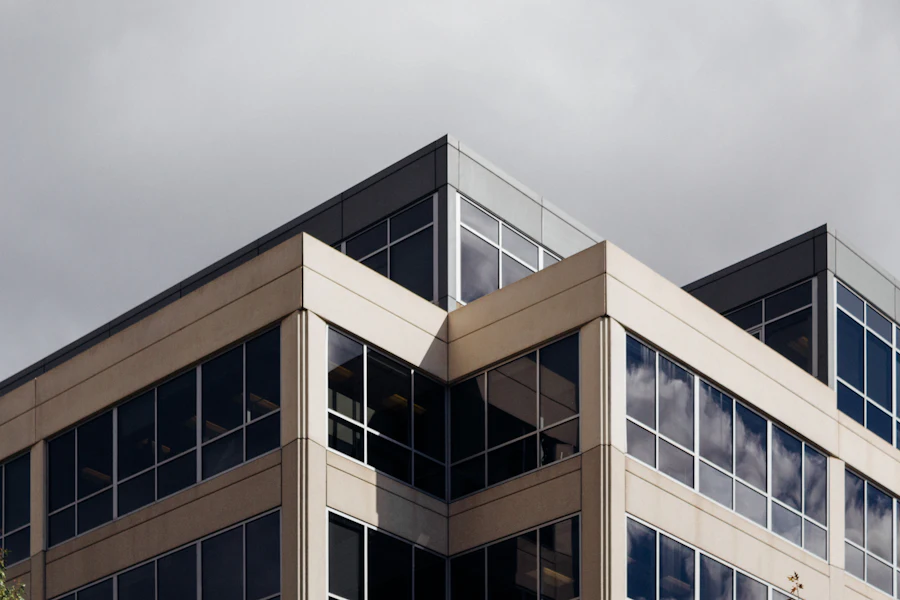 Corner of a mid-rise office building with stacked glass and stone floor plates under an overcast sky