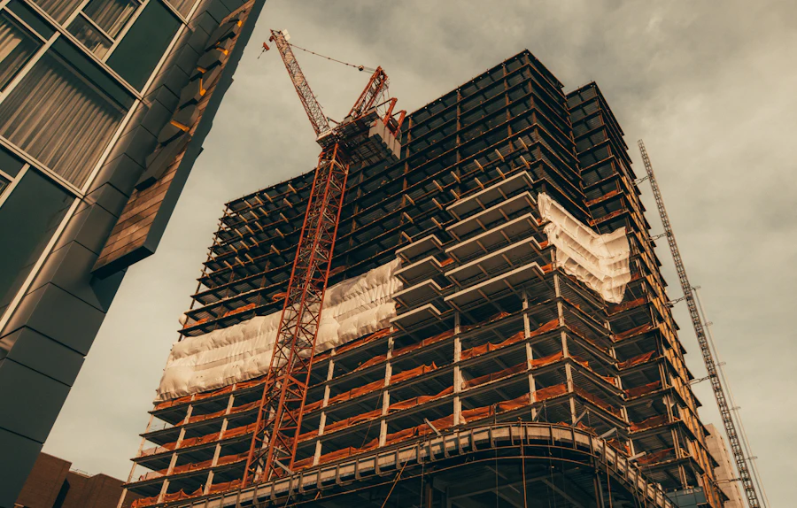 Concrete frame of a high-rise under construction seen from below, with a tower crane