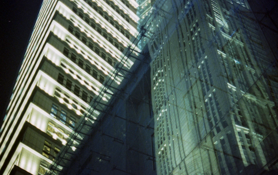 Glass office tower facade lit at night, its floor plates glowing in a regular grid